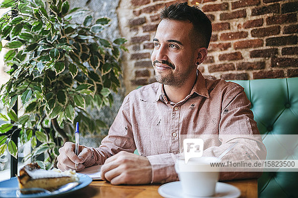 Porträt eines Mannes in einem Cafe  der Notizen macht