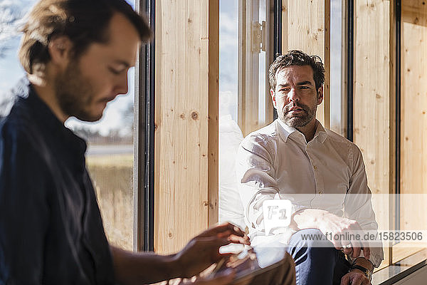 Two businessmen talking at the window in office