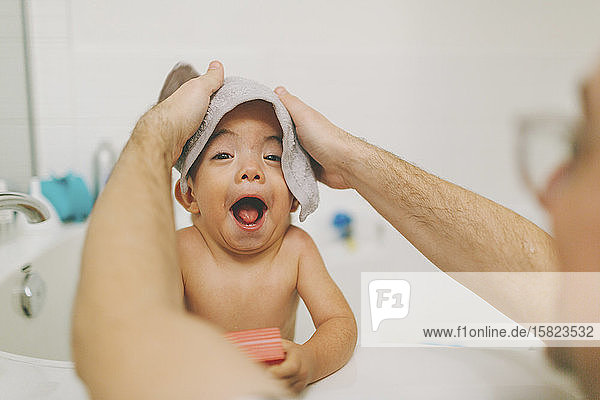 Baby macht ein lustiges Gesicht in der Badewanne