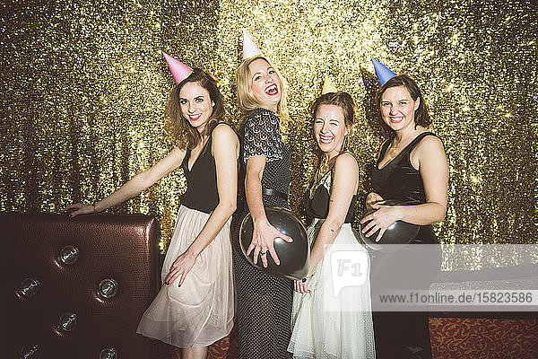 Portrait of four happy women wearing party hats in a club