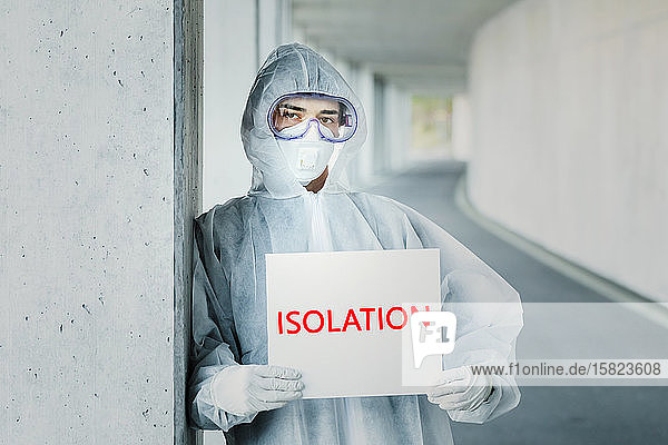 Porträt eines Mannes in Schutzkleidung mit einem Isolation -Schild