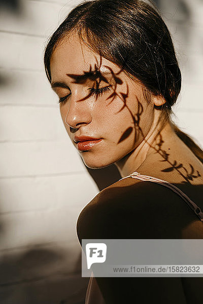 Porträt eines Teenager-Mädchens mit Blattschatten im Gesicht