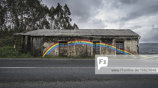 Spanien  Provinz A Coruna  San Saturnino  Regenbogen auf verlassenes Haus am Straßenrand gemalt