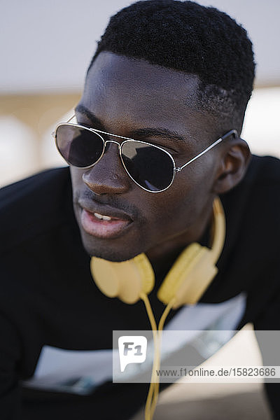 Portrait of stylish young man wearing sunglasses looking around