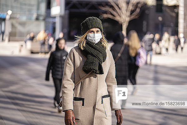 Frau mit Gesichtsmaske pendelt in der Stadt