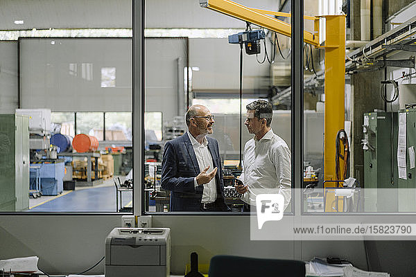 Zwei Geschäftsleute im Gespräch in einer Fabrik