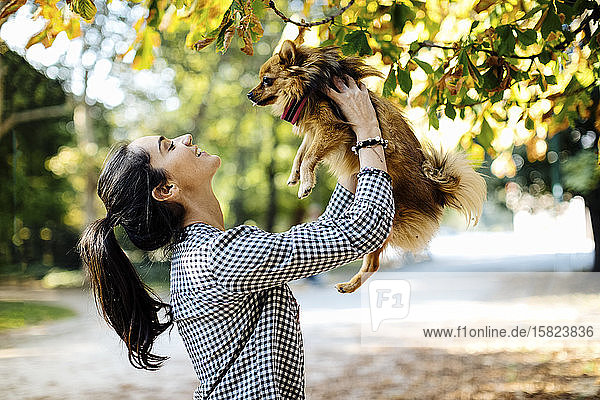 Happy young woman holding dog in a park