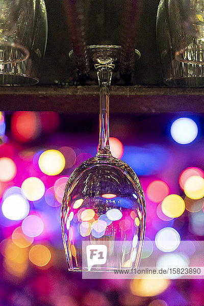 Leeres Weinglas hängt über der Theke mit Bokeh-Lichtern im Hintergrund