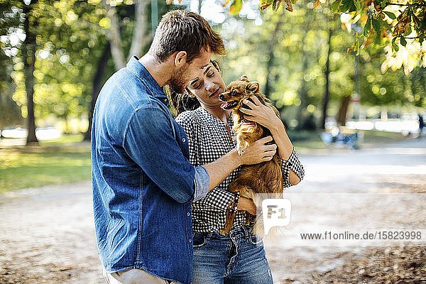 Glückliches junges Paar mit Hund in einem Park