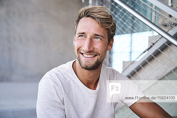 Porträt eines lächelnden jungen Mannes mit weißem T-Shirt