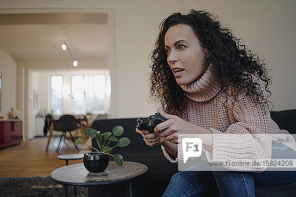 Frau sitzt auf dem Sofa  hat Spaß  spielt mit einer Spielkonsole