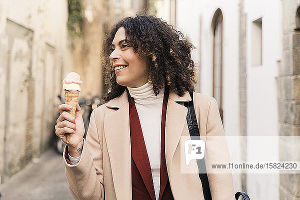 Happy woman eating an ice cream cone in an alley  Florence  Italy