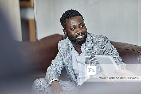 Portrait of a smiling businessman sitting on couch looking at colleague