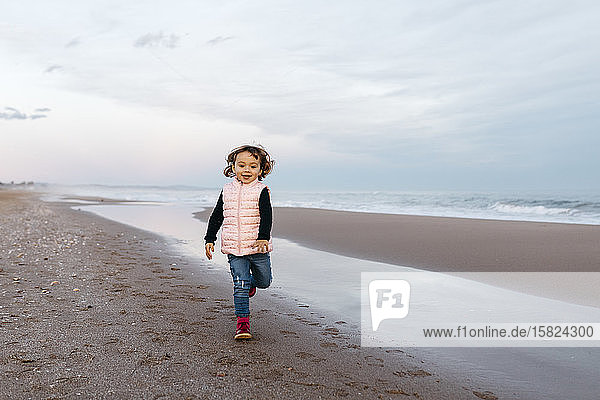 Happy girl running on the beach at sunset