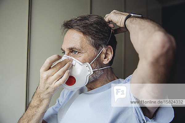 Männliches Gesundheitspersonal setzt FFP3-Maske auf