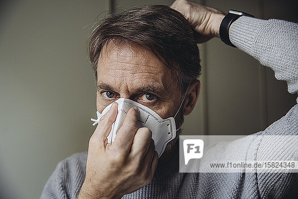 Mature man putting on protective mask