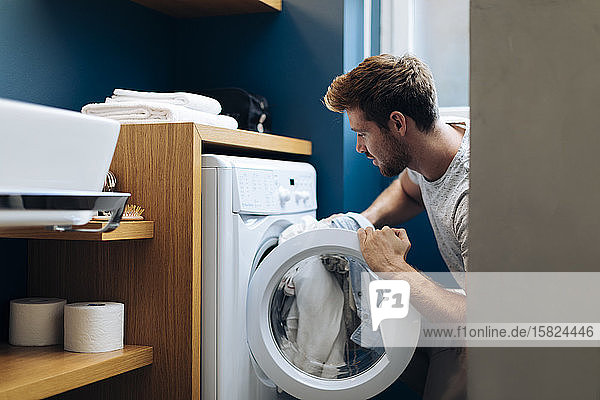 Junger Mann wäscht die Wäsche zu Hause