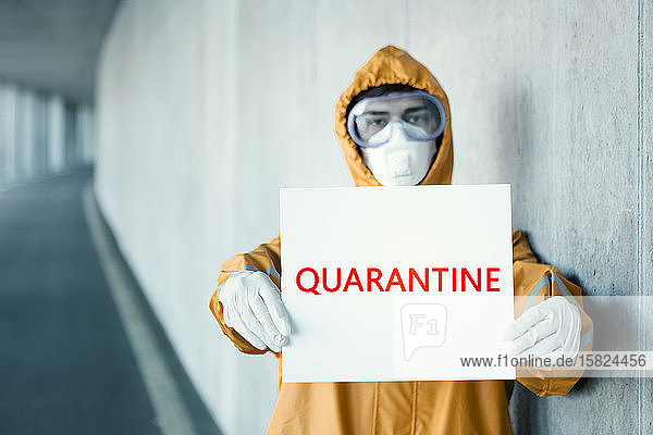 Porträt eines Mannes in Schutzkleidung mit einem Quarantäne -Schild