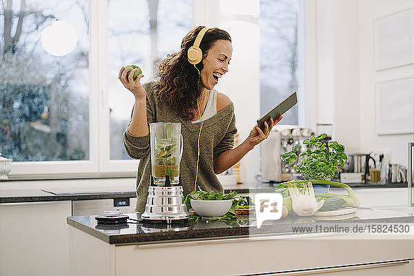 Fitte Frau steht in der Küche  bereitet gesunden Smoothie zu  mit Online-Rezept
