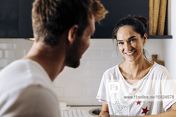 Portrait of young woman smiling at boyfriend in the kitchen