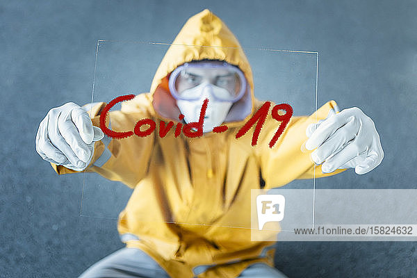 Porträt eines Mannes in Schutzkleidung mit dem Schild Covid 19