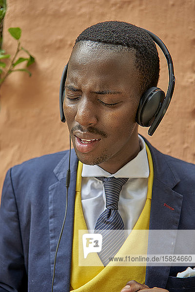 Stilvoller junger Geschäftsmann im altmodischen Anzug  der über Kopfhörer Musik hört