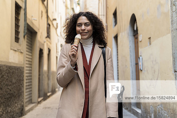 Porträt einer lächelnden Frau  die in einer Gasse eine Eistüte isst  Florenz  Italien