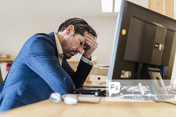 Frustrierter Geschäftsmann sitzt im Büro am Schreibtisch
