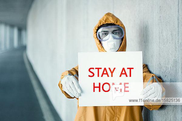 Porträt eines Mannes in Schutzkleidung mit einem Bleiben Sie zu Hause -Schild
