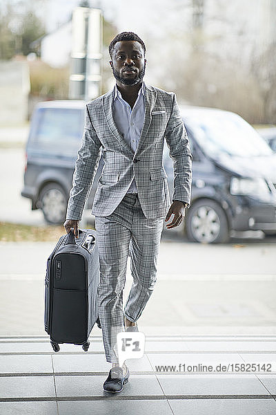 Businessman with suitcase walking on pavement