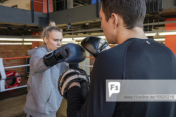 Boxerin beim Sparring mit ihrem Trainer im Fitnessstudio