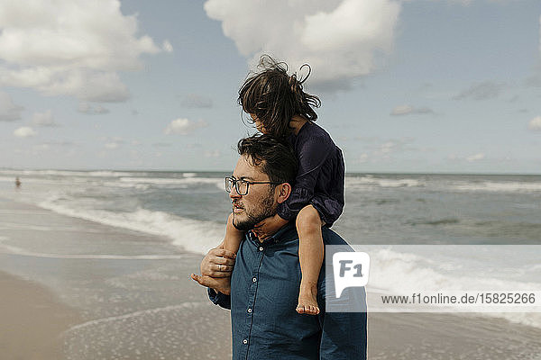 Mann trägt kleine Tochter auf versteckten Schultern am Strand  Scheveningen  Niederlande
