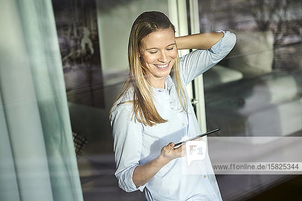 Lächelnde blonde junge Frau mit Tablette