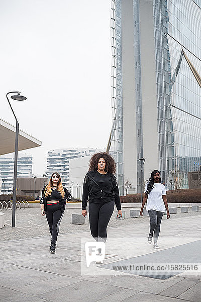 Three sportive young women walking in the city