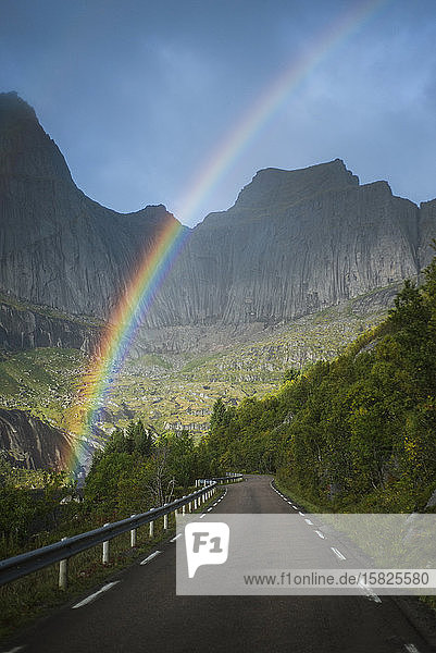 Norwegen  Lofoten  Regenbogen über leerer Straße in Berglandschaft