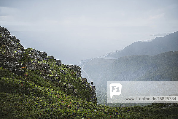 Norway  Lofoten Islands  Reine  Man looking at view fromÂ ReinebringenÂ mountain during rain