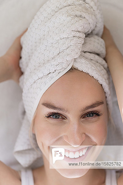 Porträt einer lächelnden Frau mit in ein Handtuch gewickeltem Kopf