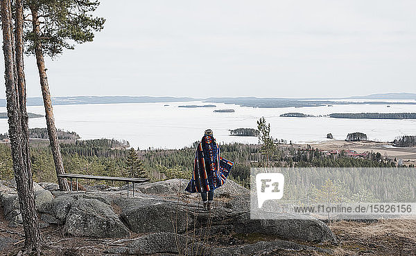Frau  die auf einem Felsen steht und die schöne Aussicht in Schweden genießt