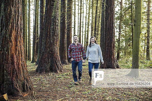 attraktives  trendiges Paar  das durch den Wald spaziert und nach vorne schaut.