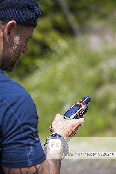 Mann navigiert beim Wandern mit einem GPS-Gerät