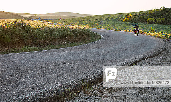 junger Biker fährt mit hoher Geschwindigkeit mit seinem Fahrrad auf dem Asphalt vor ihm