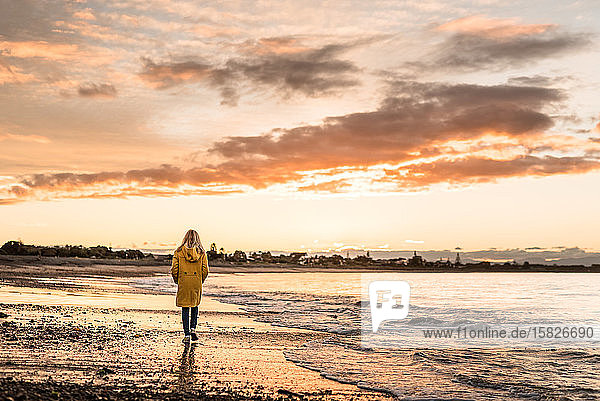 Preteen girl walking at dusk on a beach in winter