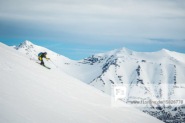 Ein Mann auf Skiern mit Bergen im Rücken in Island