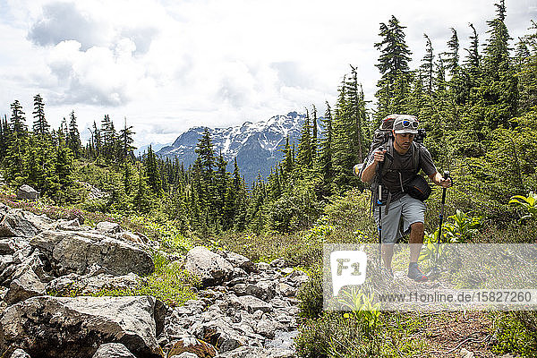 Ein Mann wandert einen Pfad entlang  um ein Wochenende in den Bergen zu zelten.