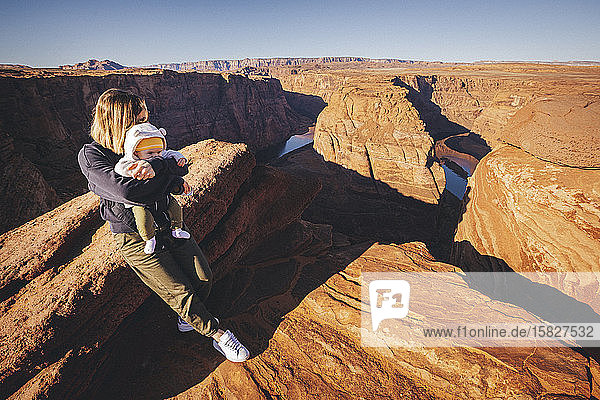 A woman with a child is sitting near Horseshoe Bend  Arizona