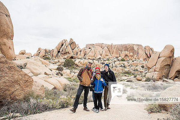 Family of four having fun surrounded by rocks and shrubs in desert