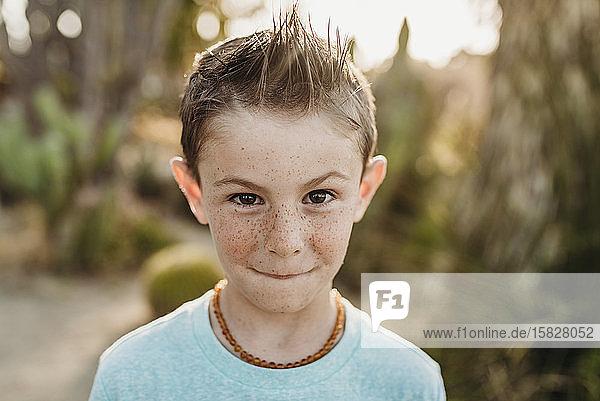 Close up portrait of cute young boy with freckles making serious face