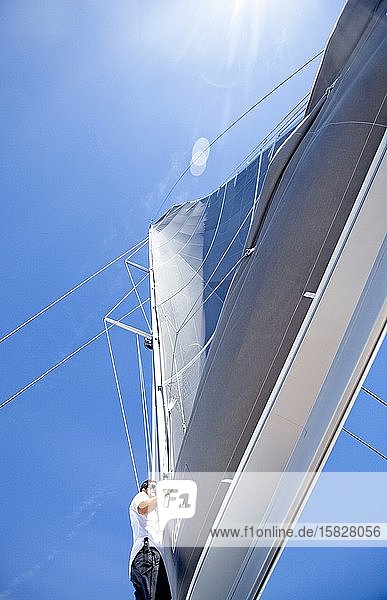 Ein Matrose auf dem Vorderdeck eines Katamarans bei der Kontrolle der Takelage