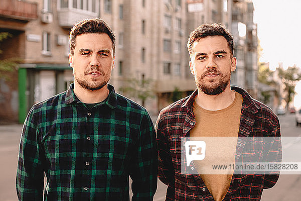 Porträt von erwachsenen Zwillingsbrüdern  die im Sommer auf der Straße der Stadt stehen