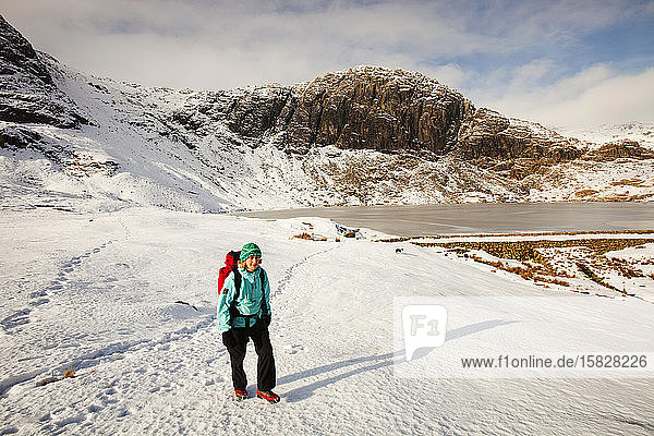 Eine Bergwanderin an einem zugefrorenen Stickle Tarn in den Langdales  Lake District  Großbritannien